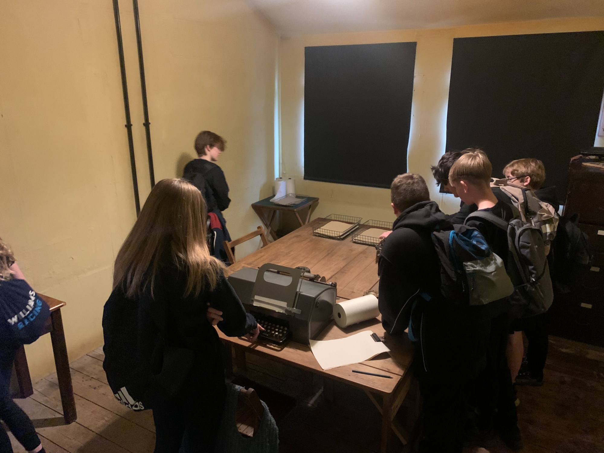 Image shows a group of pupils looking at equipment used at Bletchely Park in one of the huts