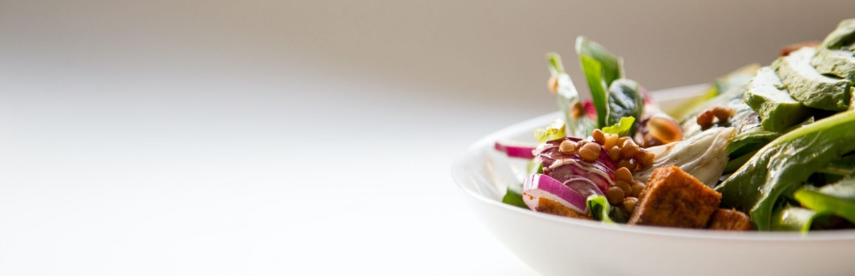 Image shows a side-on view of a plate of salad with croutons and beans