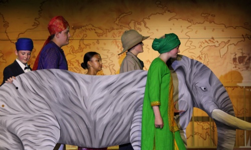 Image shows main characters walking with an elephant.